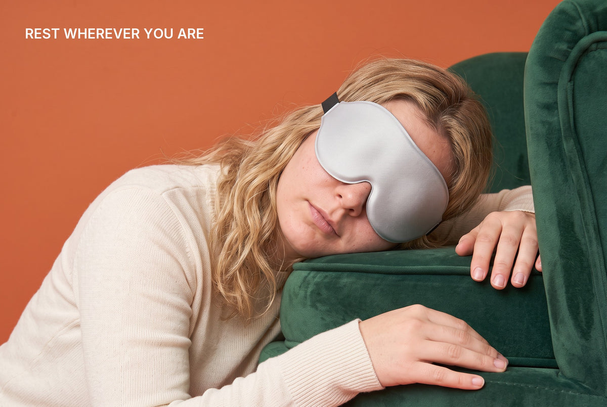Woman asleep in an armchair with the AerPack 3D Sleep Mask in Grey: rest wherever you are
